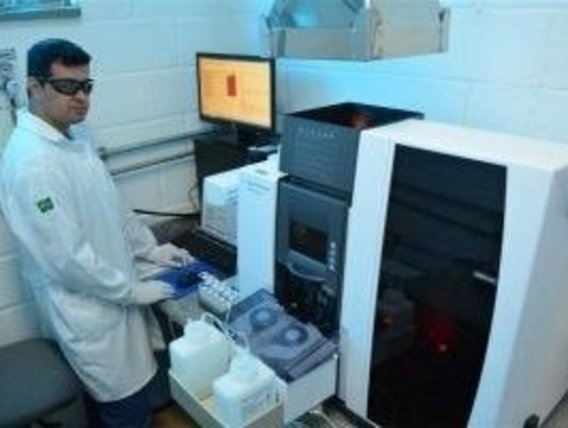Technician carrying out water analysis test Um técnico fica em frente a um dispositivo e realiza análises da água.