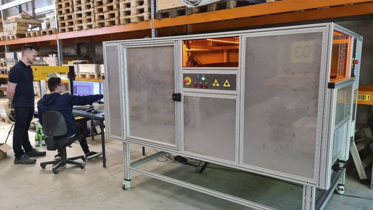 Ancorelog Ancorelog instalada em um depósito. Um homem senta-se ao lado dele em uma cadeira e mostra a um segundo homem algo no computador.