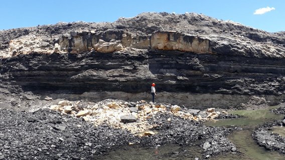 Pessoa diante de uma montanha de pedras Pessoa diante de uma montanha de pedras